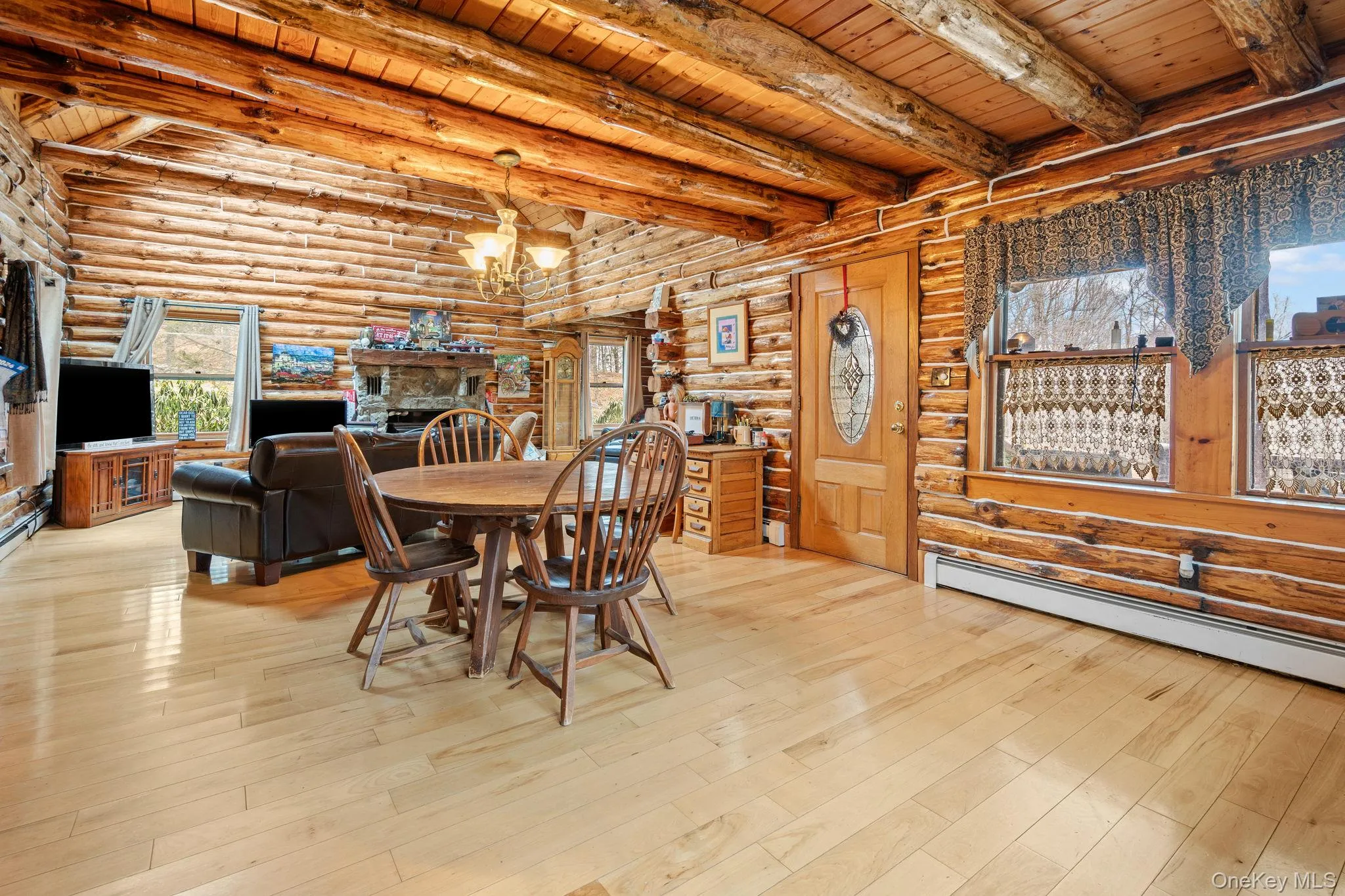 Dining area with a wooden ceiling with exposed beams, a chandelier, rustic walls, wood finished floors, and a baseboard heating unit Dining area with a wooden ceiling with exposed beams, a chandelier, rustic walls, wood finished floors, and a baseboard heating unit