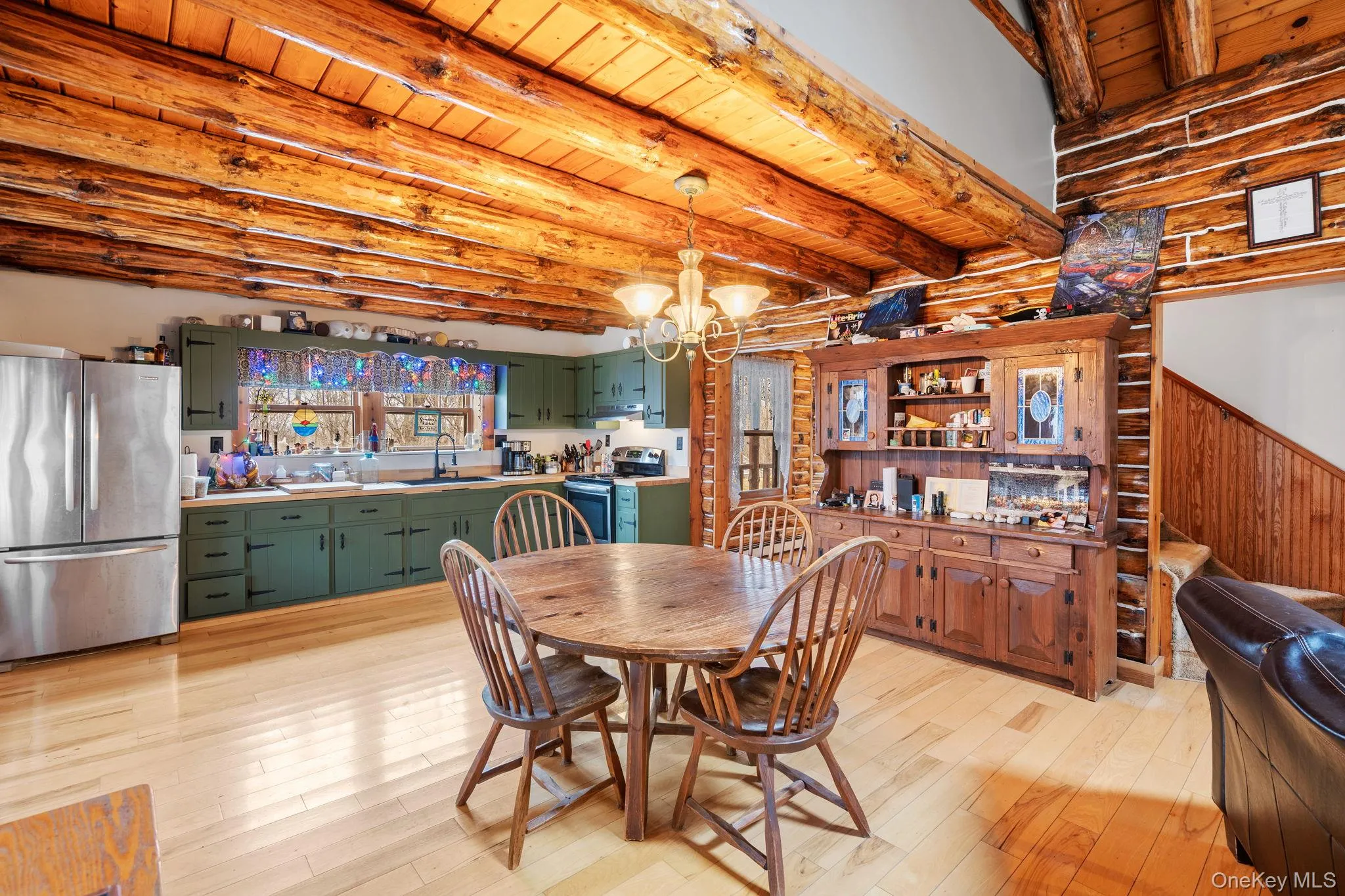 Dining room with a chandelier, light wood-style floors, a wood ceiling with exposed beams, and log walls Dining room with a chandelier, light wood-style floors, a wood ceiling with exposed beams, and log walls