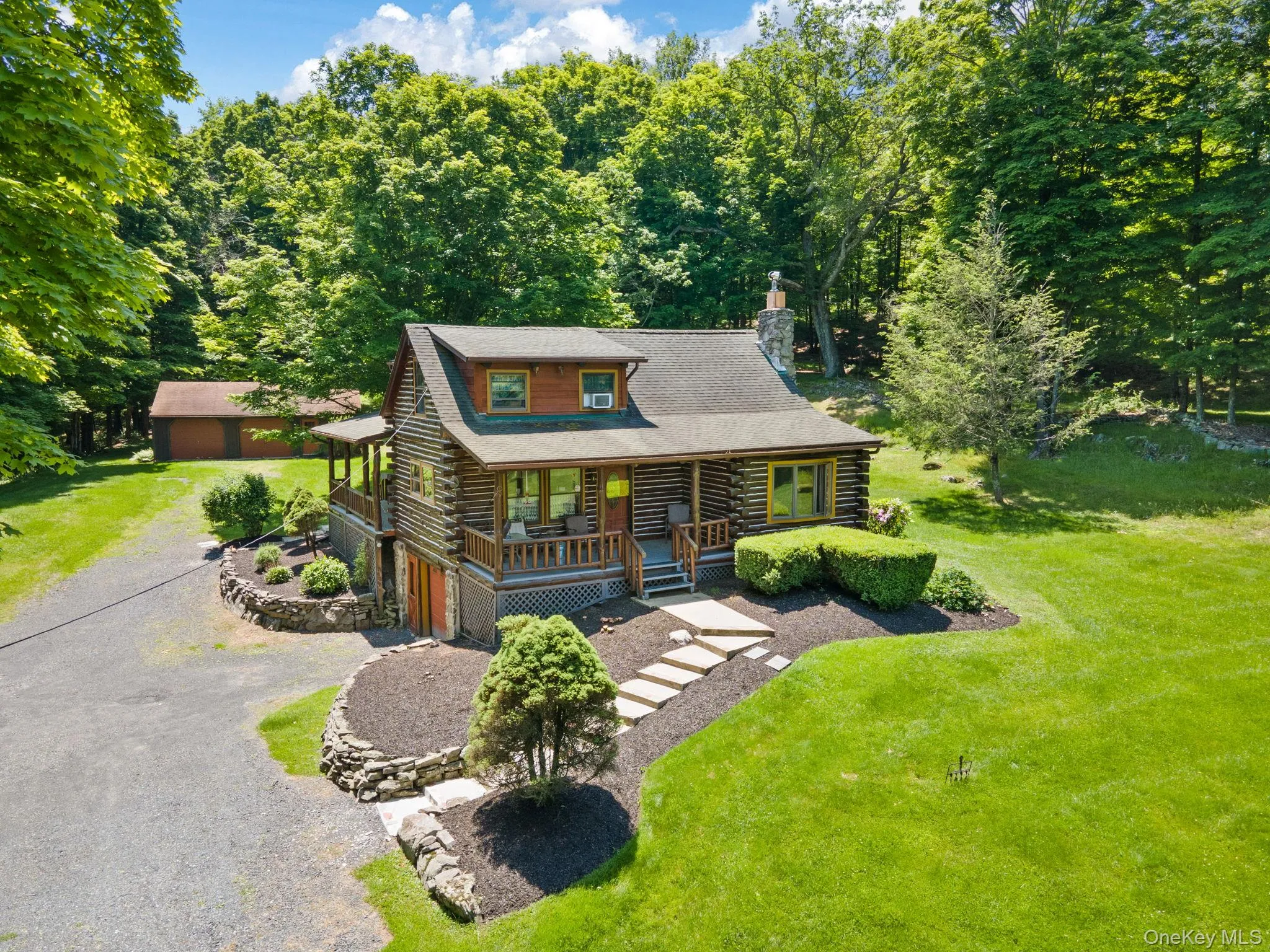 Cabin with log exterior, a porch, a chimney, driveway, and a front yard Cabin with log exterior, a porch, a chimney, driveway, and a front yard