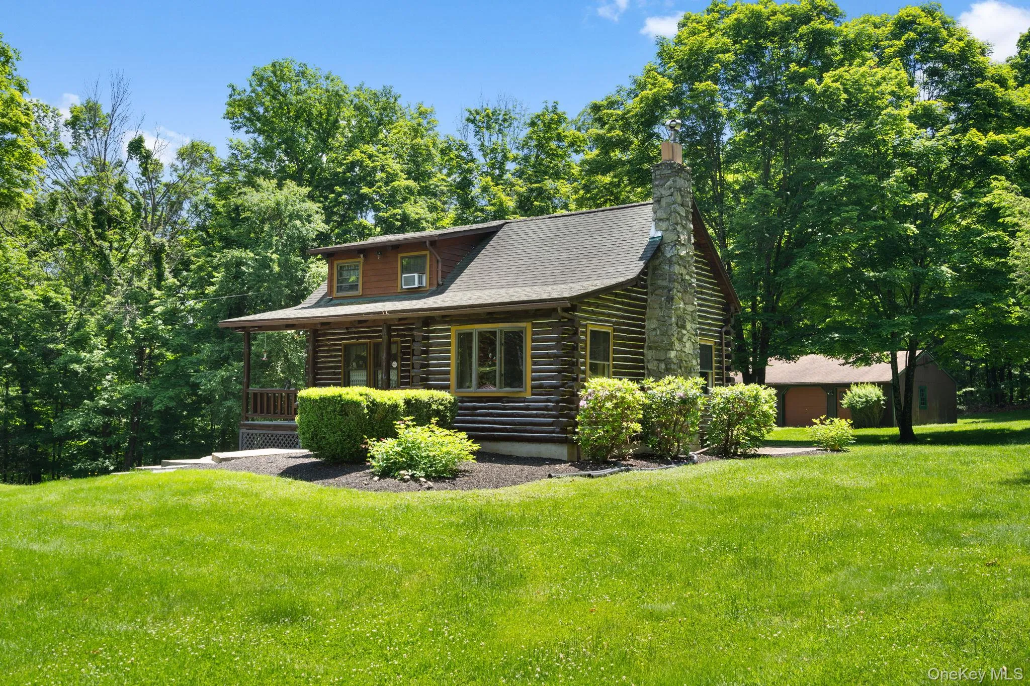 Log home featuring log siding, a front yard, covered porch, and a chimney Log home featuring log siding, a front yard, covered porch, and a chimney