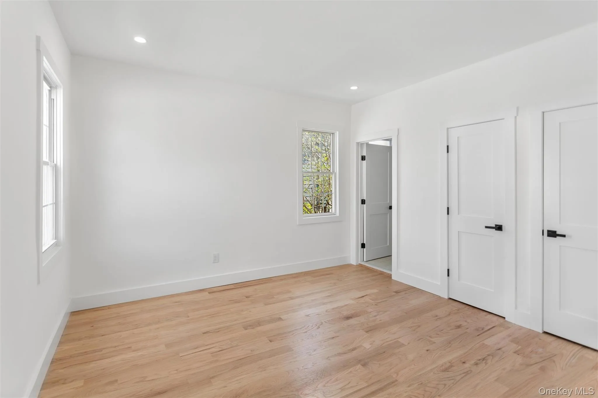 This room features hardwood floors, white walls, and recessed lighting This room features hardwood floors, white walls, and recessed lighting