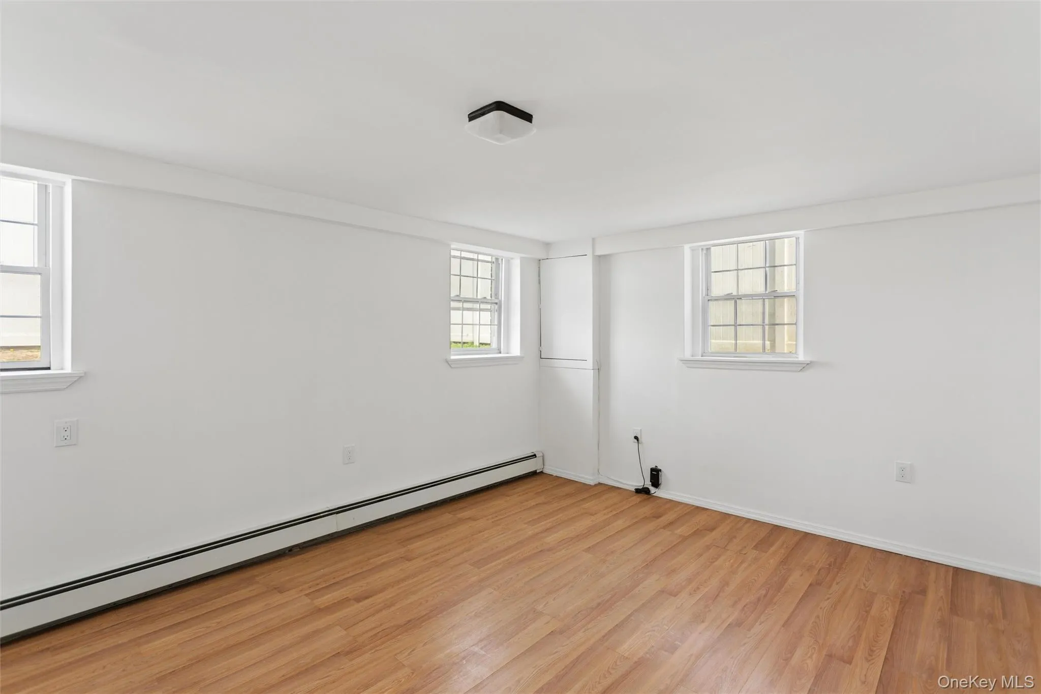 The room features light wood-style flooring, white walls, and two windows providing natural light The room features light wood-style flooring, white walls, and two windows providing natural light