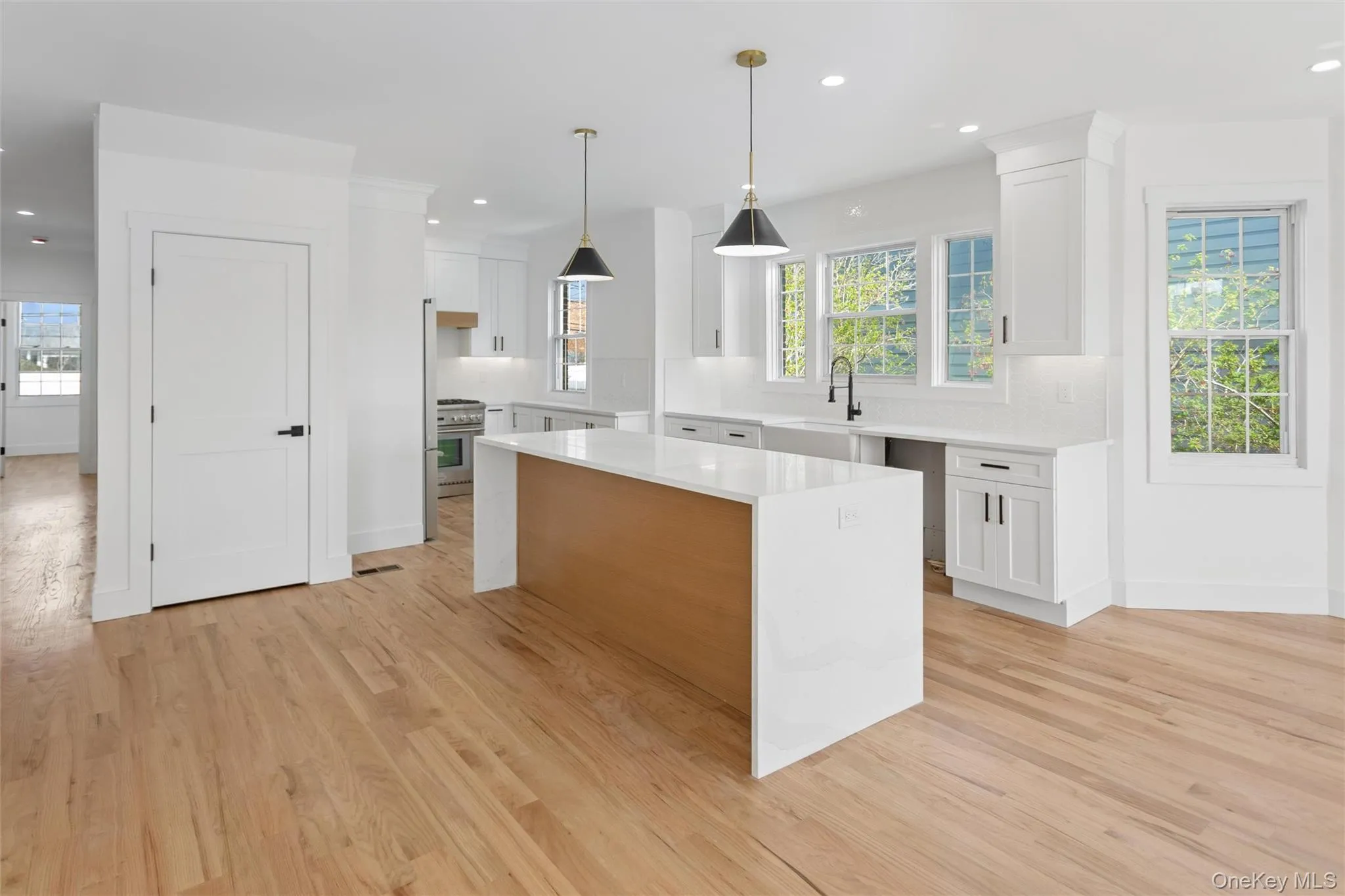 This kitchen features a central island with a light wood base and a white countertop, complemented by white cabinetry and light hardwood flooring This kitchen features a central island with a light wood base and a white countertop, complemented by white cabinetry and light hardwood flooring