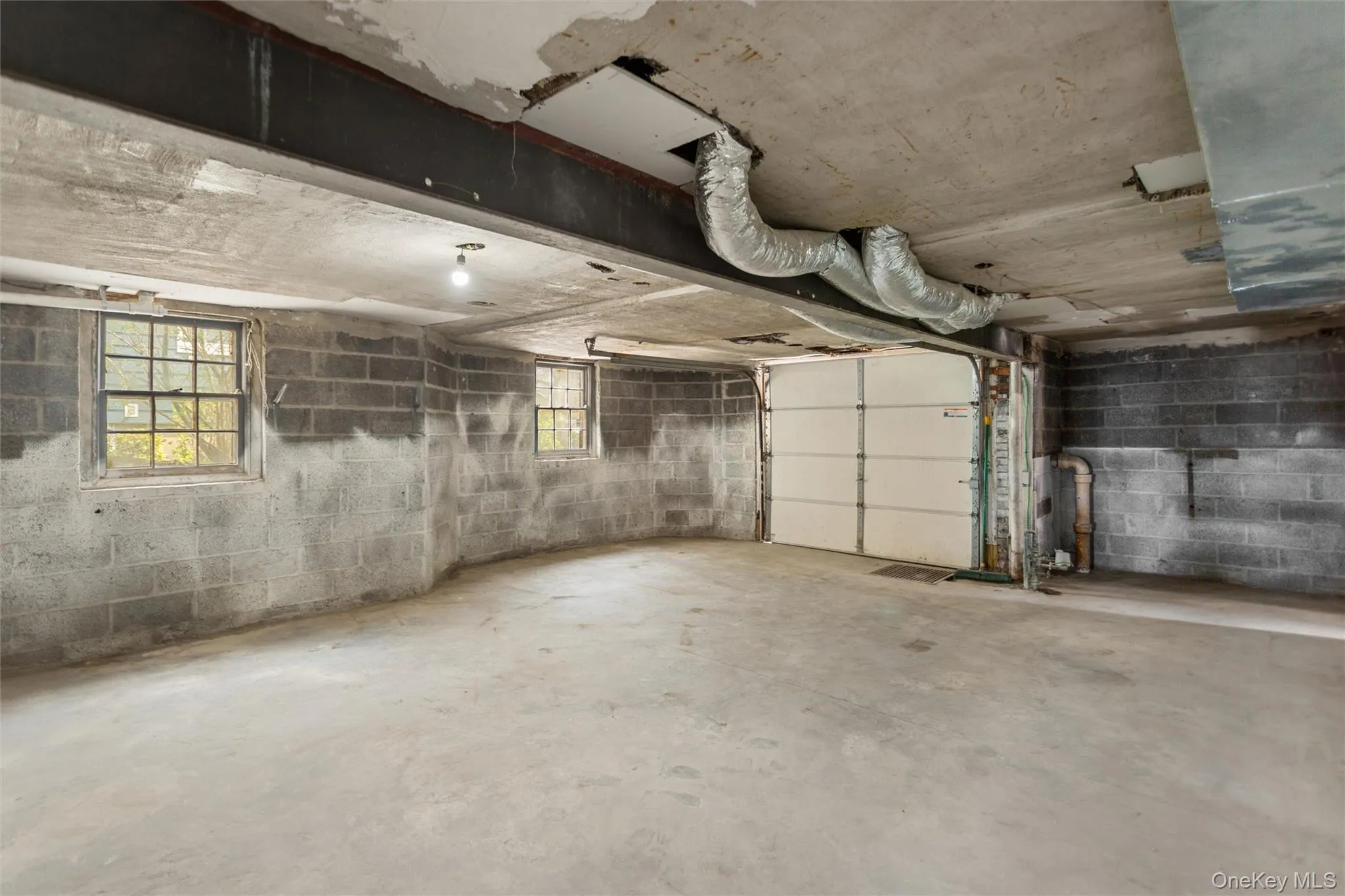 Spacious garage area featuring a concrete floor, exposed block walls, and overhead garage door Spacious garage area featuring a concrete floor, exposed block walls, and overhead garage door