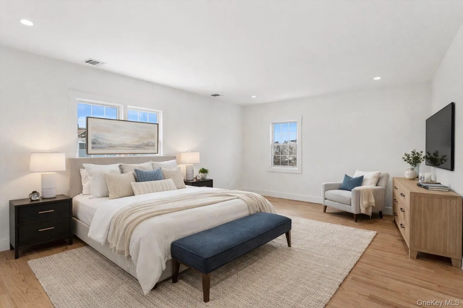 Staged Photo Spacious room featuring hardwood floors, recessed lighting, and ample natural light from multiple windows Staged Photo Spacious room featuring hardwood floors, recessed lighting, and ample natural light from multiple windows