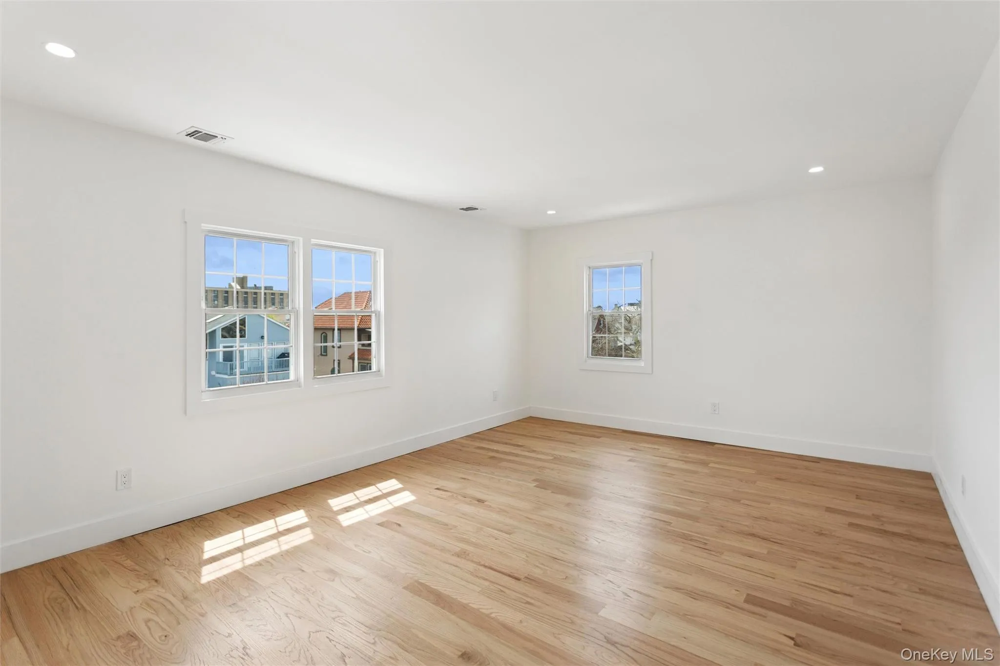 A bright room featuring light hardwood floors, white walls, and recessed lighting A bright room featuring light hardwood floors, white walls, and recessed lighting