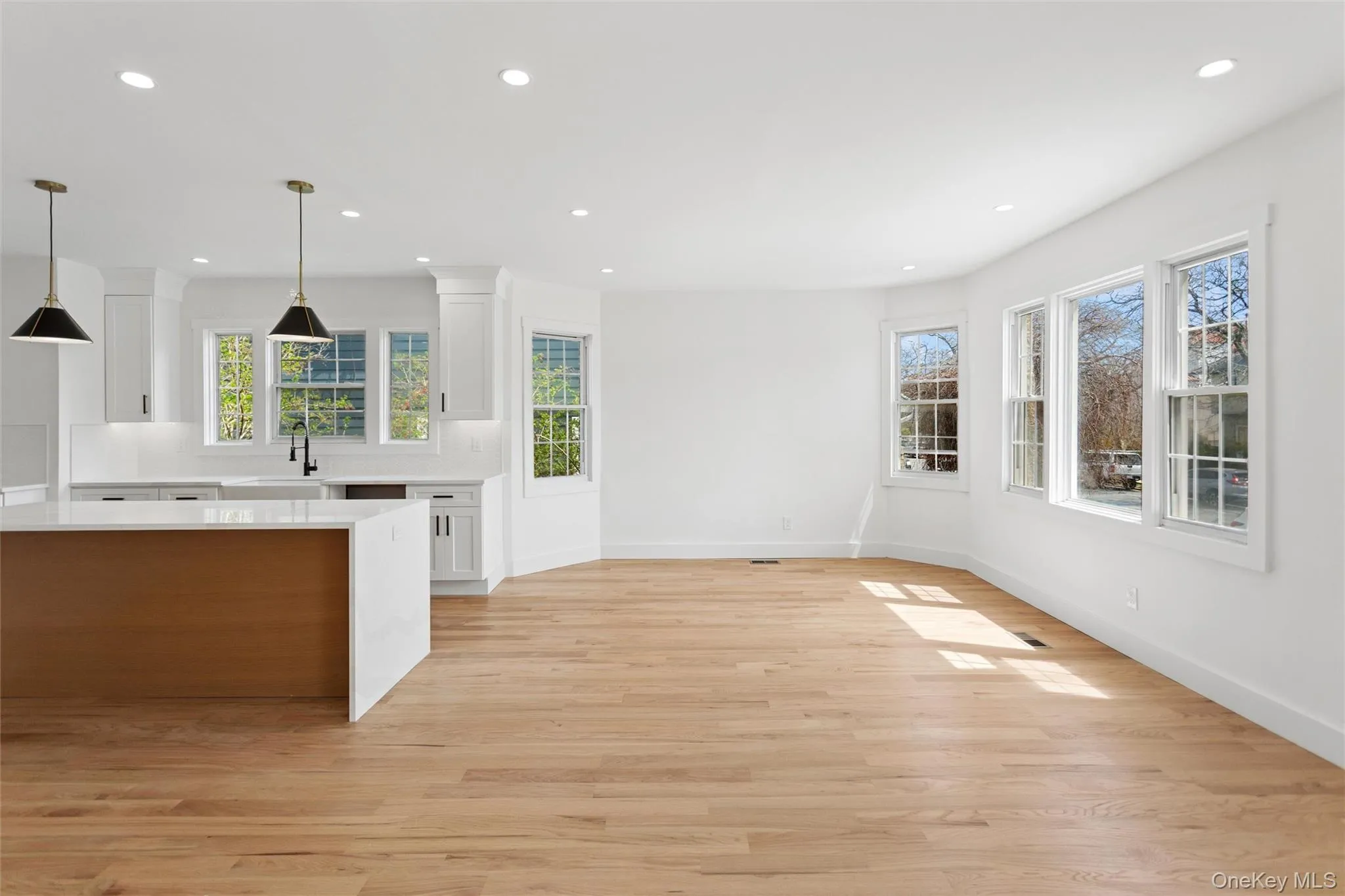 This open concept living space features light wood flooring, white walls, and recessed lighting This open concept living space features light wood flooring, white walls, and recessed lighting