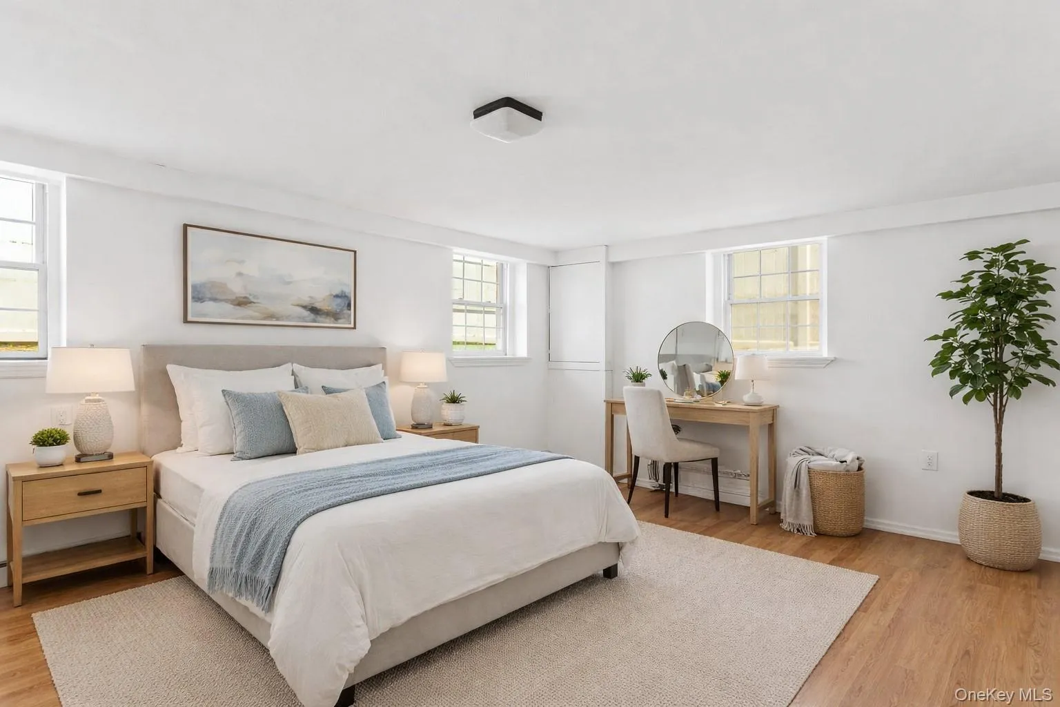 Staged PhotoThis bedroom features light wood flooring and white walls, creating a bright and airy atmosphere Staged PhotoThis bedroom features light wood flooring and white walls, creating a bright and airy atmosphere