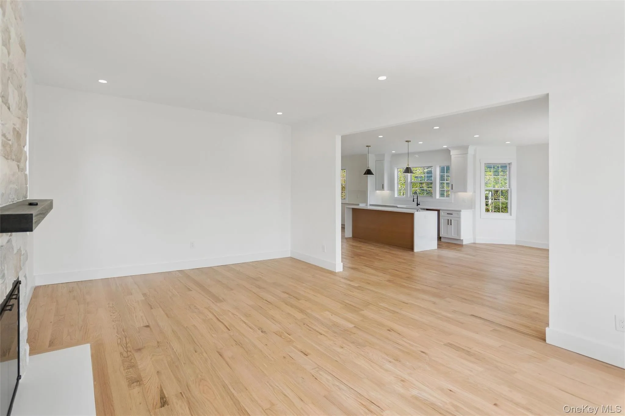This property features light hardwood floors throughout the living area, leading into an open-concept kitchen with white cabinetry and an island This property features light hardwood floors throughout the living area, leading into an open-concept kitchen with white cabinetry and an island
