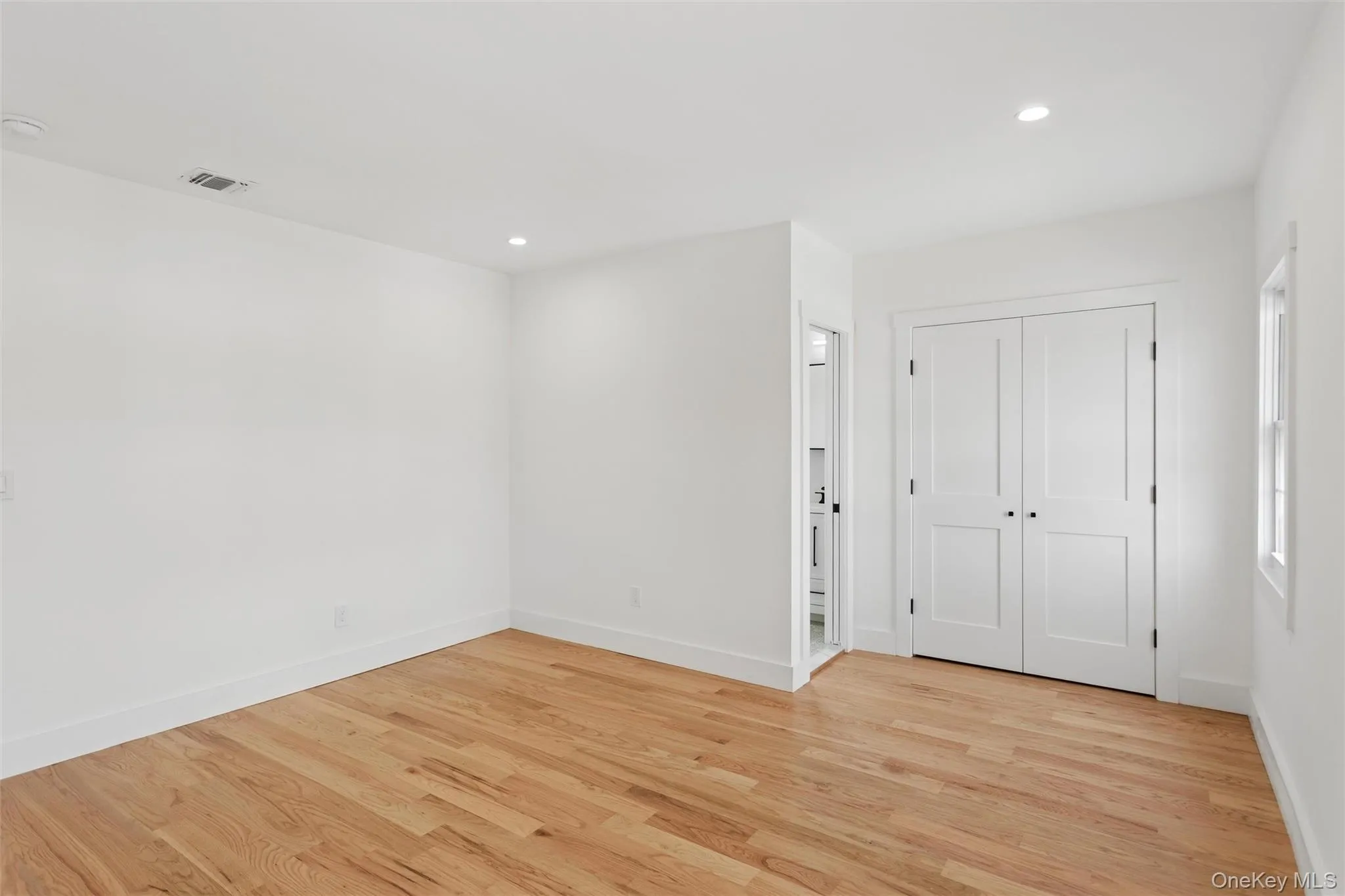 The room features light-toned hardwood flooring, recessed lighting, and white walls The room features light-toned hardwood flooring, recessed lighting, and white walls