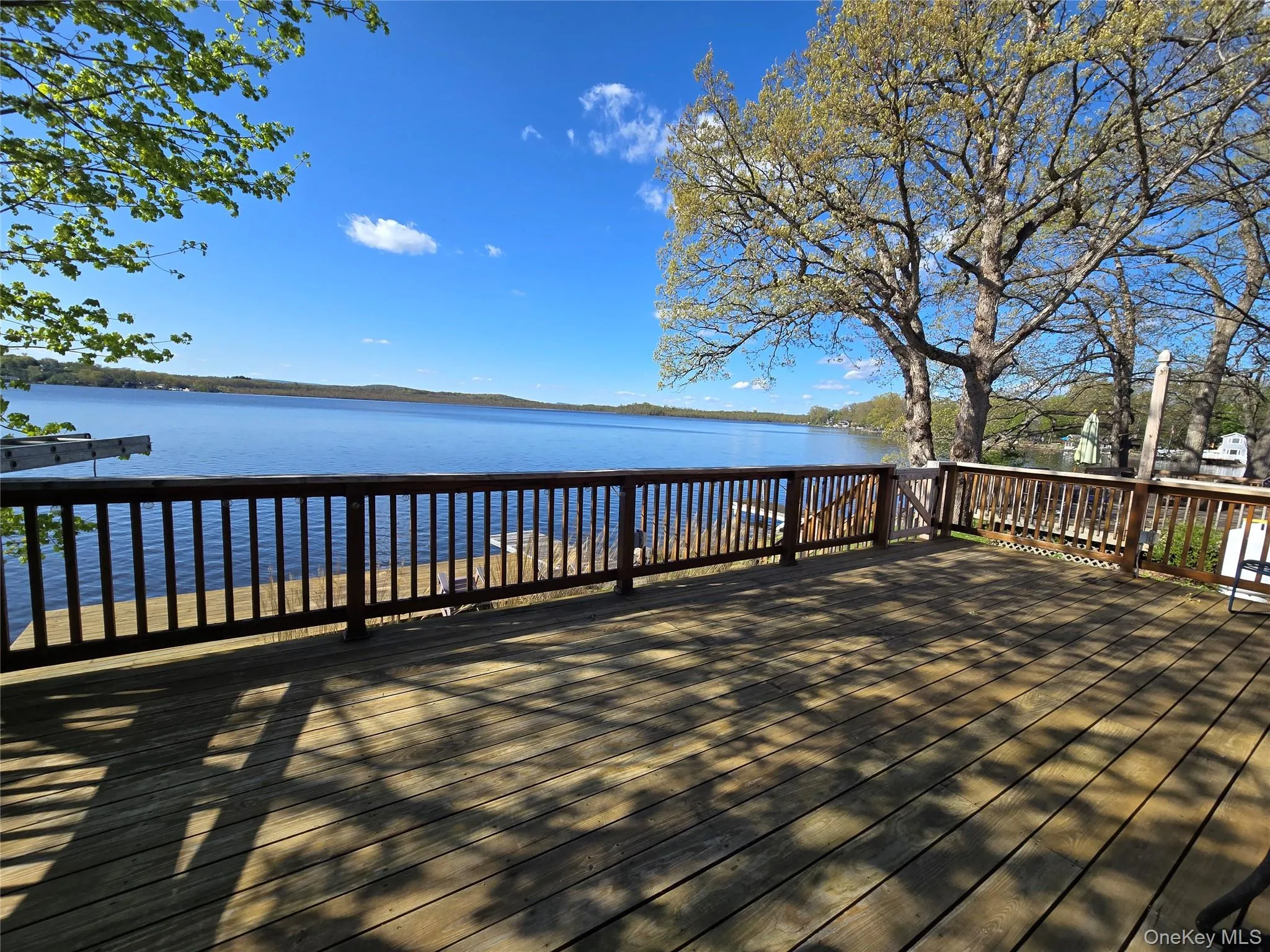 Expansive wood deck featuring a baluster railing system, offering direct water frontage Expansive wood deck featuring a baluster railing system, offering direct water frontage
