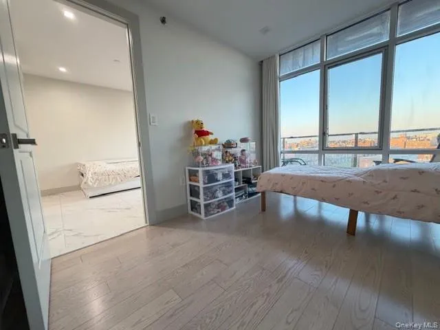 Bedroom featuring expansive windows and light wood-style flooring Bedroom featuring expansive windows and light wood-style flooring