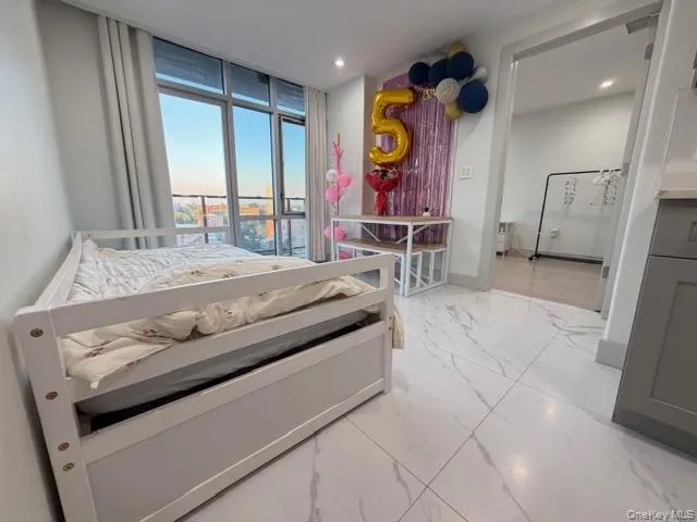 Bedroom with light marble finish floors, floor to ceiling windows, and recessed lighting Bedroom with light marble finish floors, floor to ceiling windows, and recessed lighting