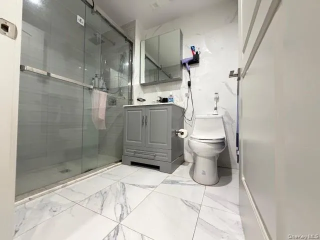 Bathroom with vanity, a shower stall, and light marble finish flooring Bathroom with vanity, a shower stall, and light marble finish flooring