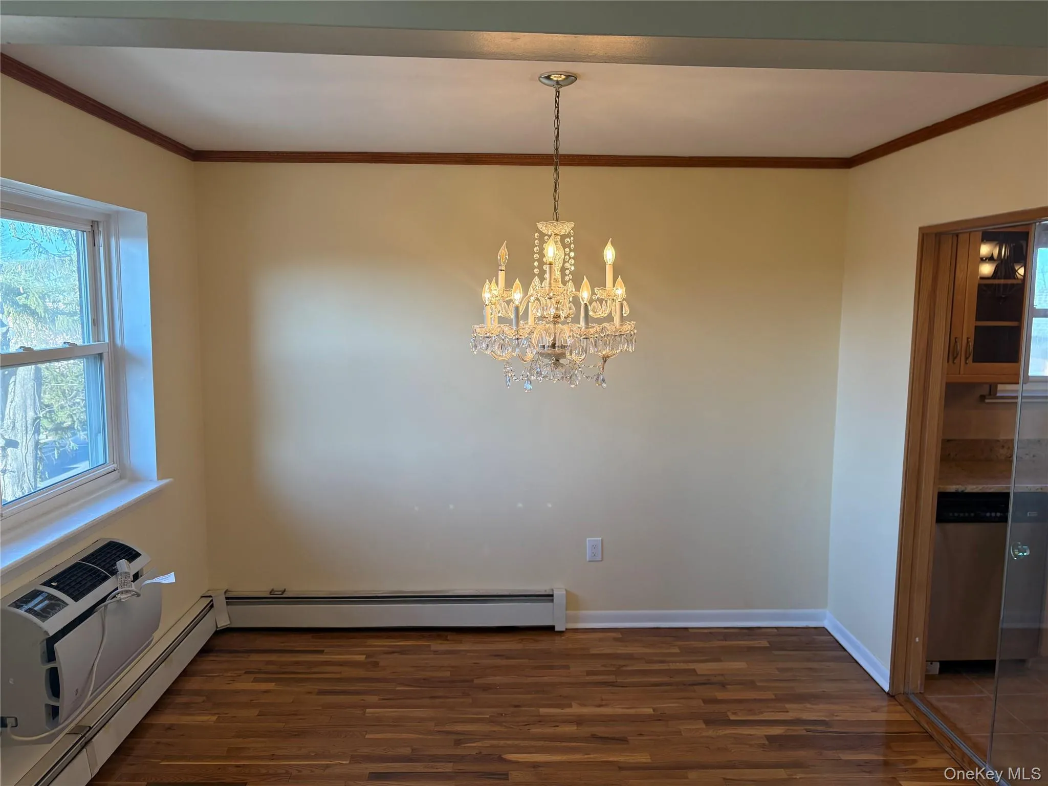Dining room featuring ornamental molding, baseboard heating, wood floors, and suspended lighting Dining room featuring ornamental molding, baseboard heating, wood floors, and suspended lighting