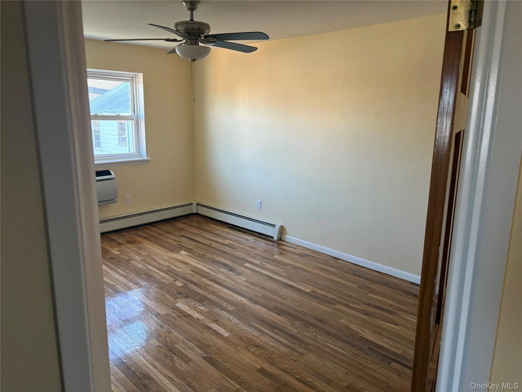 Master bedroom with wood-floors, ceiling fan, and baseboard heating Master bedroom with wood-floors, ceiling fan, and baseboard heating