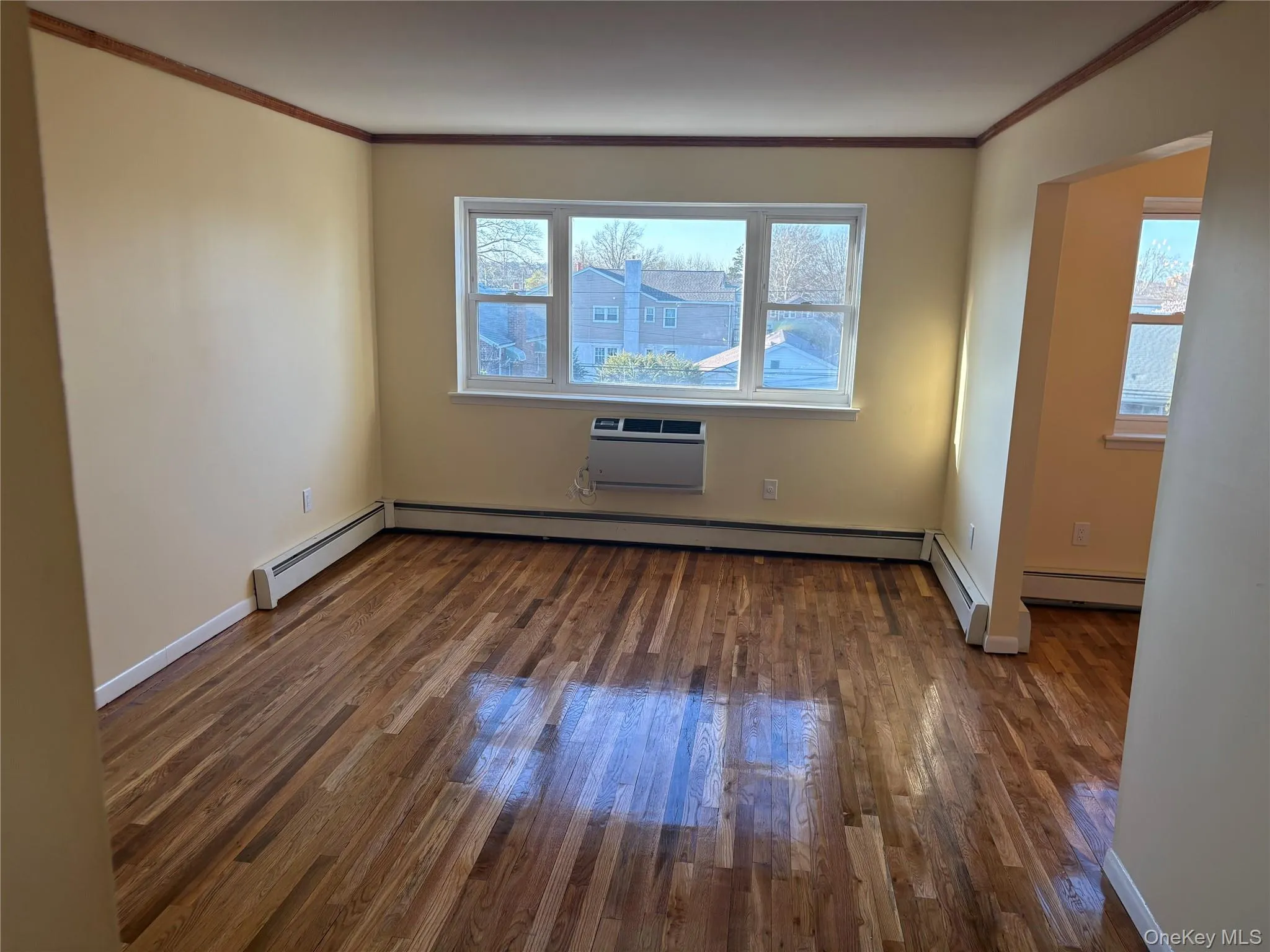 Living room featuring wood- flooring, ornamental molding, and baseboard heating Living room featuring wood- flooring, ornamental molding, and baseboard heating