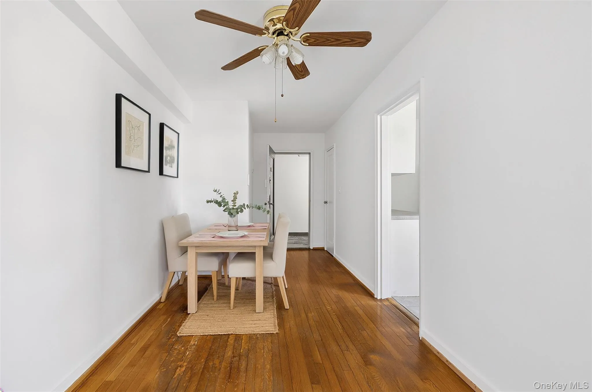 Dining area featuring wood-finish flooring, a ceiling fan with light fixture, and bright white wall finishes Dining area featuring wood-finish flooring, a ceiling fan with light fixture, and bright white wall finishes