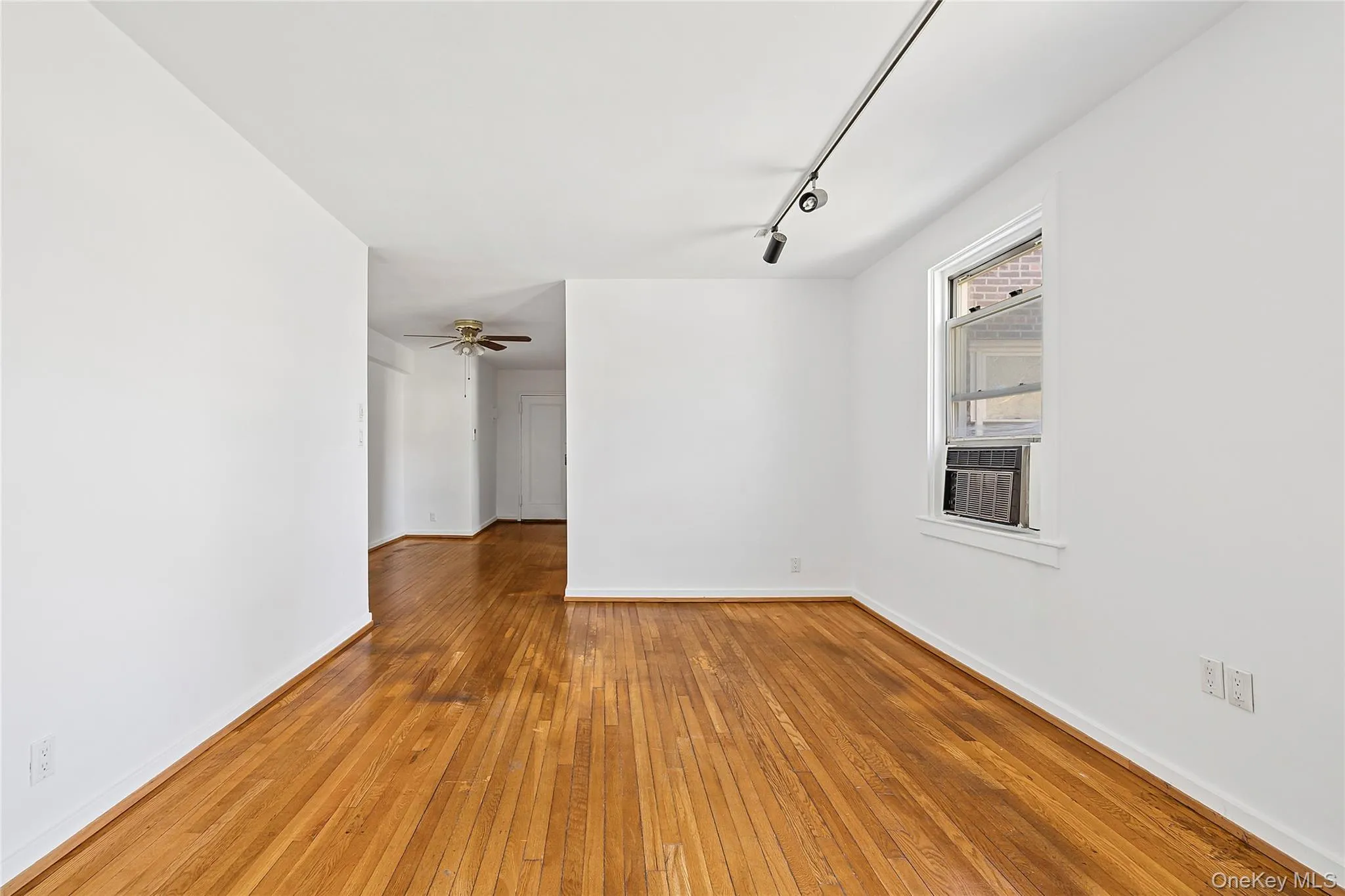 Unfurnished room featuring track lighting, wood-type flooring, ceiling fan, and cooling unit Unfurnished room featuring track lighting, wood-type flooring, ceiling fan, and cooling unit