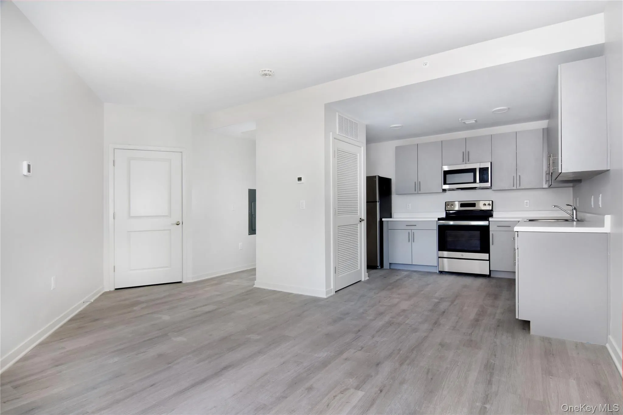 Kitchen with light countertops, appliances with stainless steel finishes, gray cabinetry, and light wood-type flooring Kitchen with light countertops, appliances with stainless steel finishes, gray cabinetry, and light wood-type flooring
