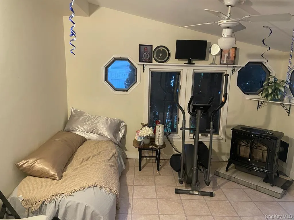 Bedroom with vaulted ceiling, a wood stove, and light tile patterned floors Bedroom with vaulted ceiling, a wood stove, and light tile patterned floors