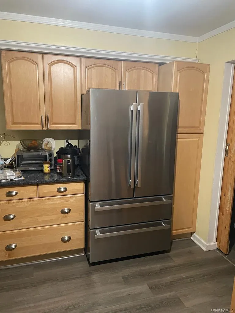 Kitchen featuring crown molding, dark countertops, light brown cabinets, and freestanding refrigerator Kitchen featuring crown molding, dark countertops, light brown cabinets, and freestanding refrigerator