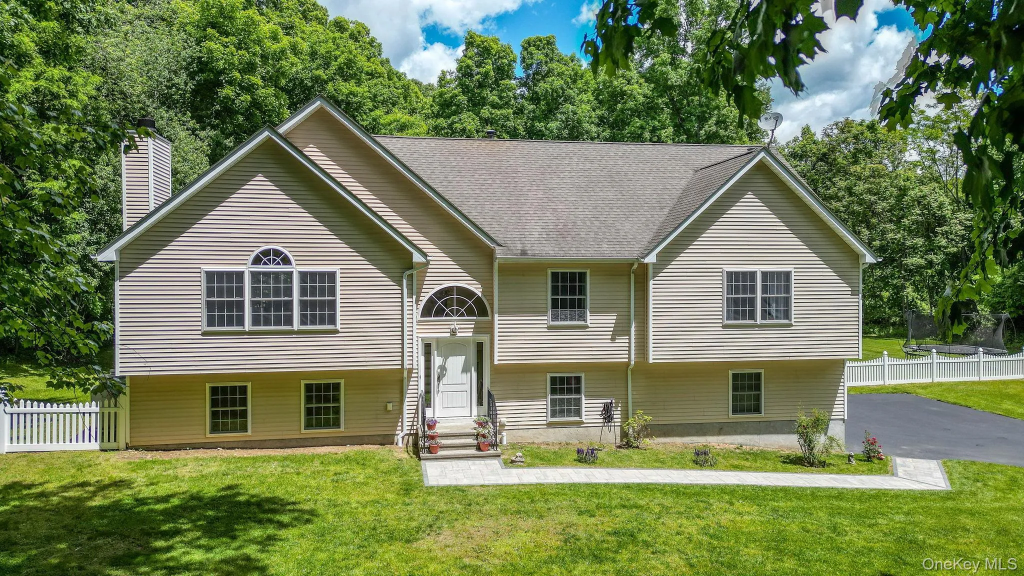 Contemporary Split-level residence featuring light-toned siding, a multi-gabled roofline, and a prominent front entrance with an arched transom window Contemporary Split-level residence featuring light-toned siding, a multi-gabled roofline, and a prominent front entrance with an arched transom window