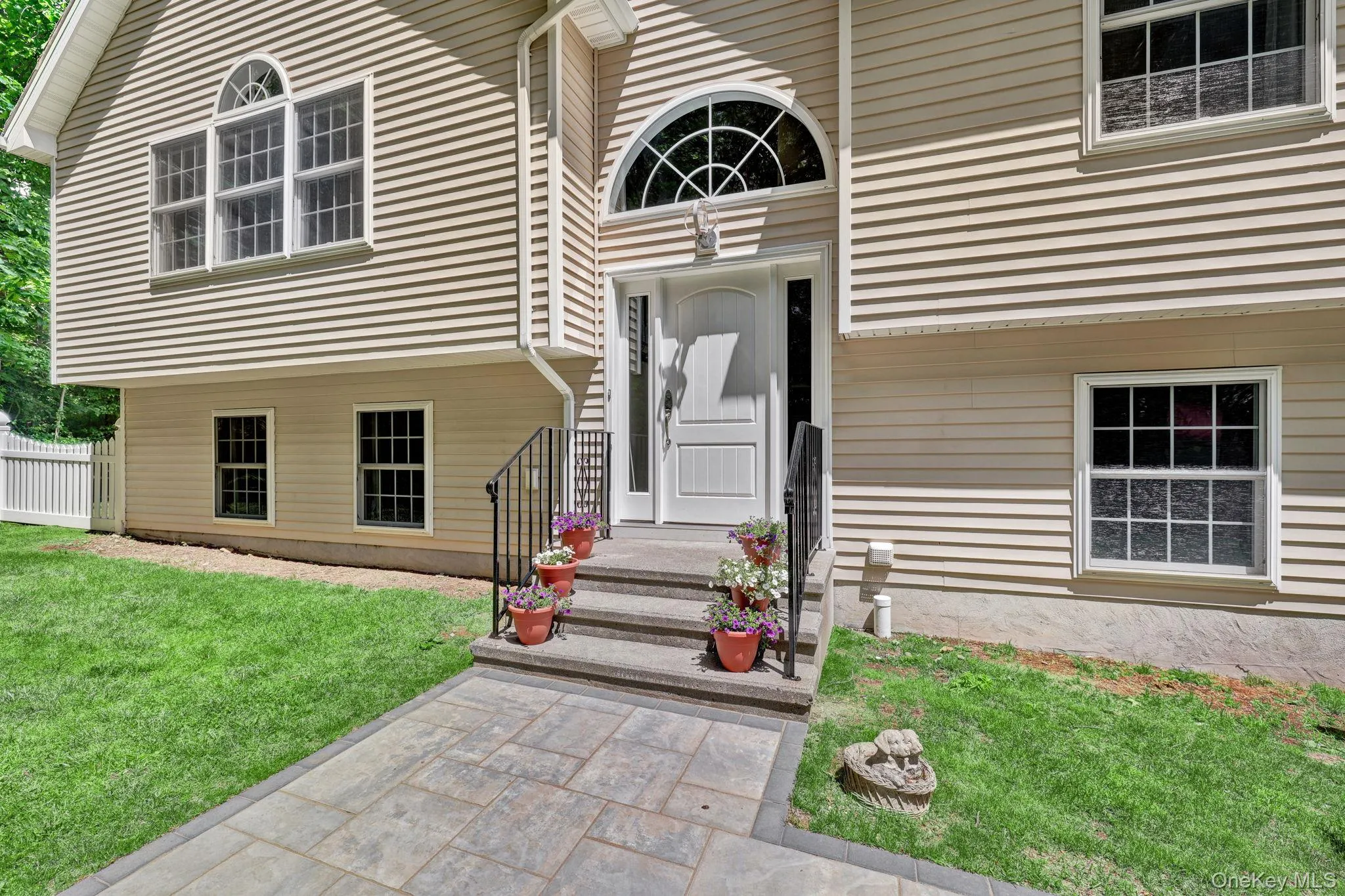 Exterior featuring neutral-toned siding, a decorative arched transom window above the entry, a new paver walkway, and a picket fence Exterior featuring neutral-toned siding, a decorative arched transom window above the entry, a new paver walkway, and a picket fence