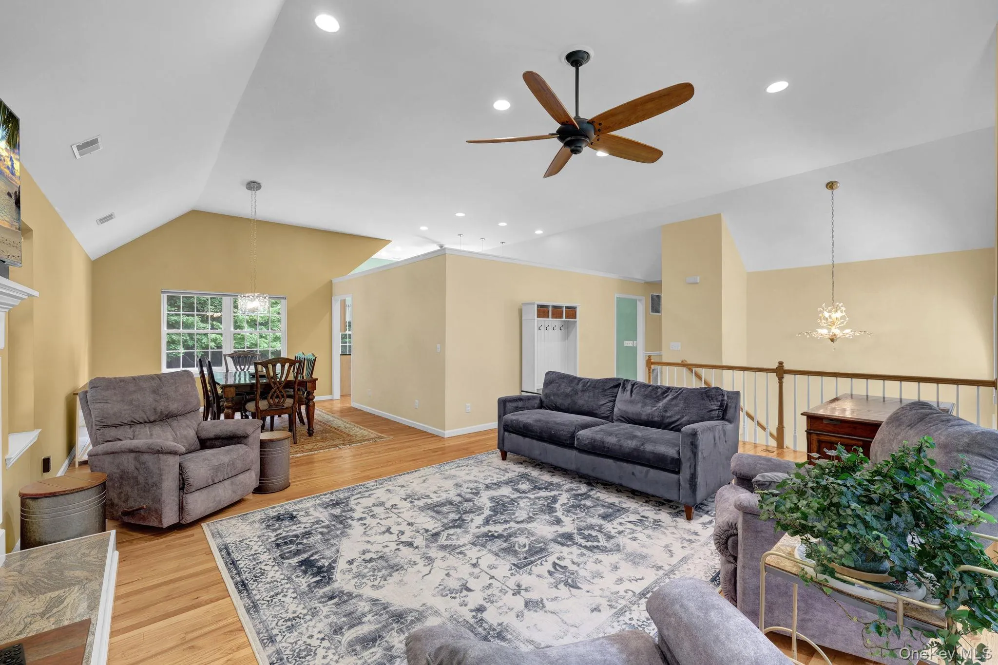 Spacious living area featuring light wood-finish flooring, a vaulted ceiling with recessed lighting, and a ceiling fan Spacious living area featuring light wood-finish flooring, a vaulted ceiling with recessed lighting, and a ceiling fan
