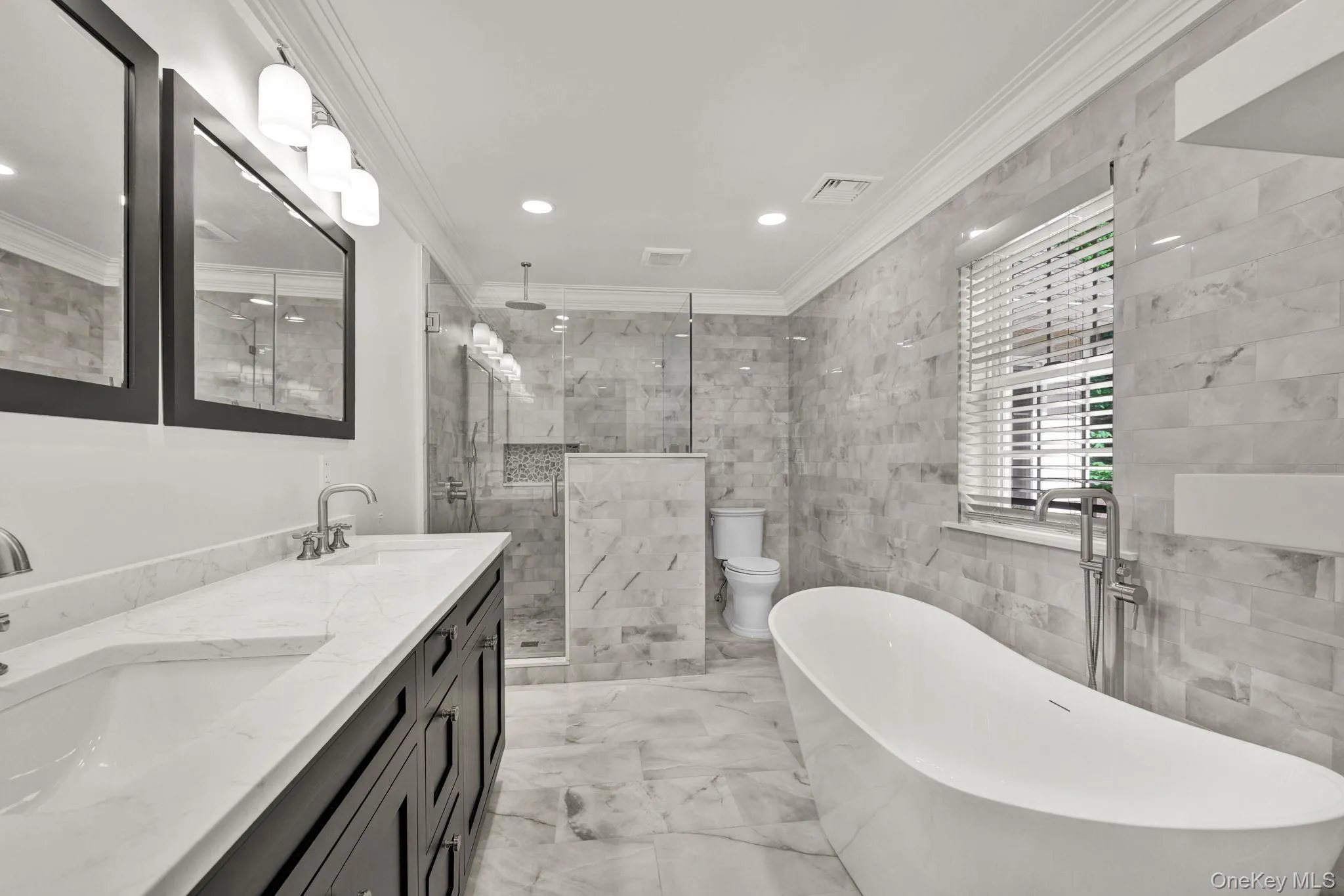 Completely and newly renovated master bathroom features a freestanding soaking tub, frameless glass shower enclosure with a rain shower head, and a double vanity with undermount sinks and a gorgeous stone countertop Completely and newly renovated master bathroom features a freestanding soaking tub, frameless glass shower enclosure with a rain shower head, and a double vanity with undermount sinks and a gorgeous stone countertop