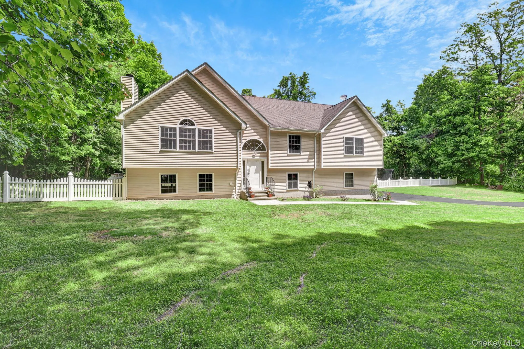 Contemporary residence featuring a neutral-toned facade, multiple gables, and a prominent arched window above the entry Contemporary residence featuring a neutral-toned facade, multiple gables, and a prominent arched window above the entry
