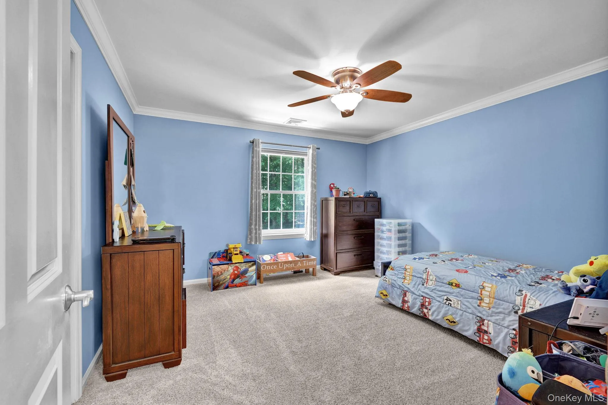 Bedroom featuring a ceiling fan with integrated lighting, crown molding, a window with exterior tree views and painted walls Bedroom featuring a ceiling fan with integrated lighting, crown molding, a window with exterior tree views and painted walls