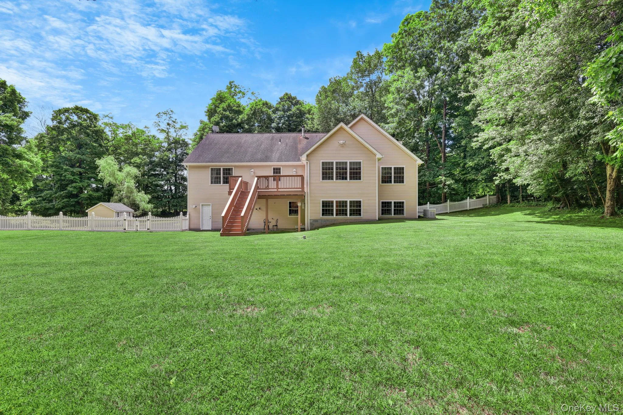 Green lawn surrounds the rear of the property, featuring a two-story beige exterior with multiple windows Green lawn surrounds the rear of the property, featuring a two-story beige exterior with multiple windows