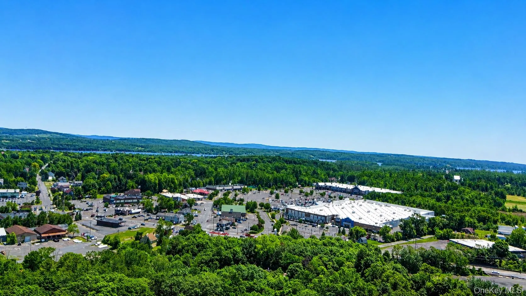 Expansive aerial of a commercial and residential area with extensive green spaces and a distant body of water Expansive aerial of a commercial and residential area with extensive green spaces and a distant body of water