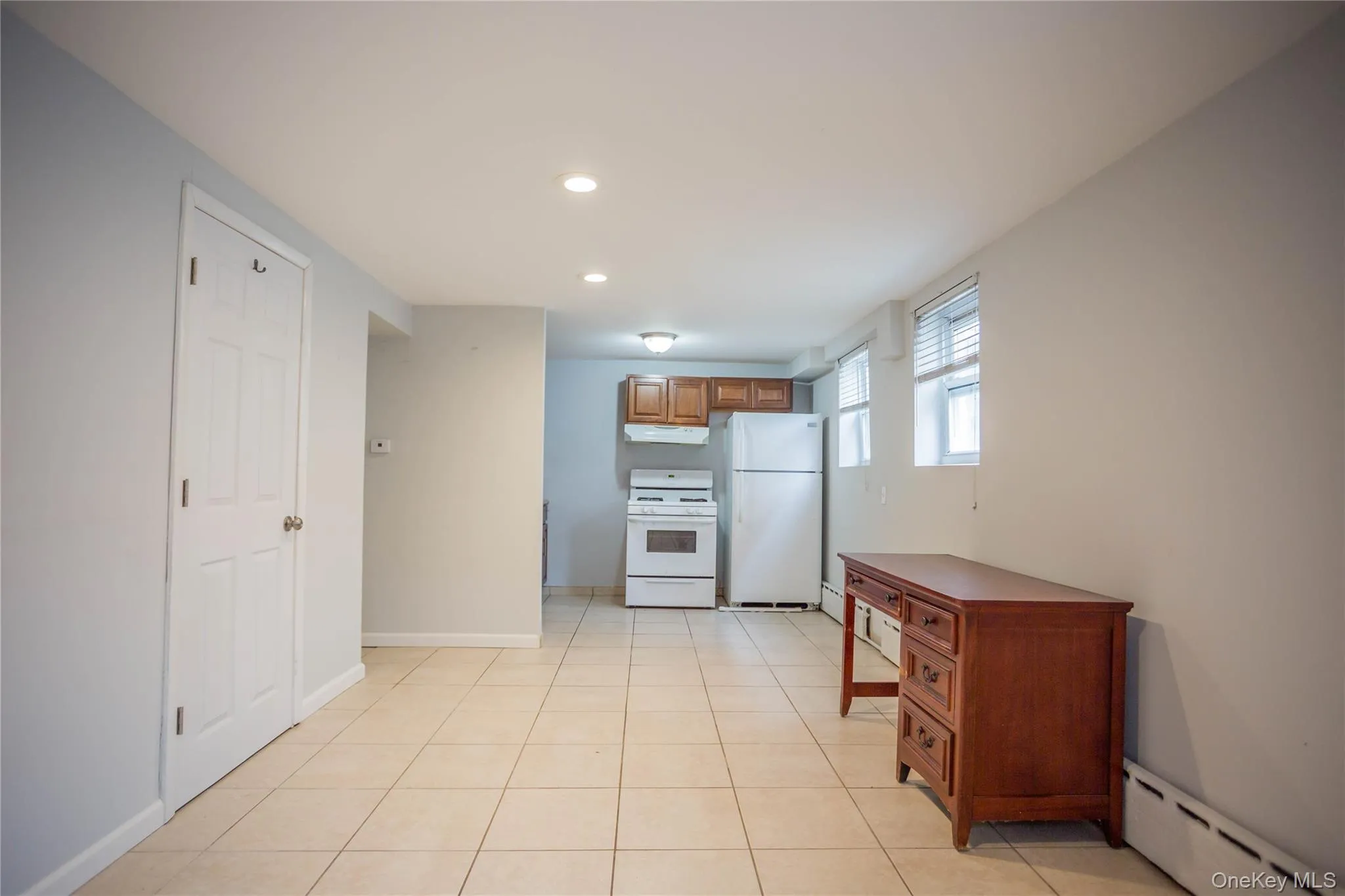 Kitchen featuring white appliances, recessed lighting, under cabinet range hood, a baseboard heating unit, and baseboards Kitchen featuring white appliances, recessed lighting, under cabinet range hood, a baseboard heating unit, and baseboards