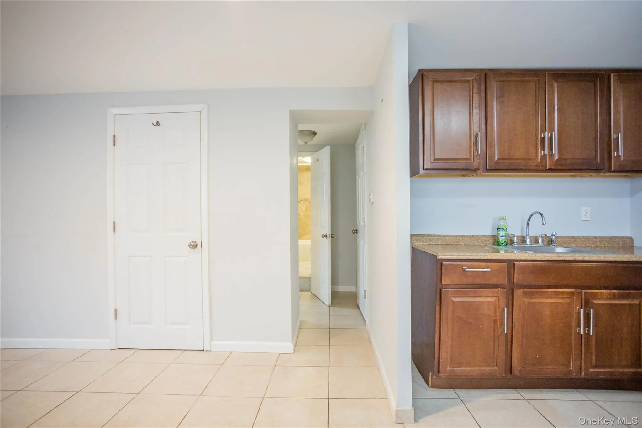 Kitchen featuring light countertops, light tile patterned floors, baseboards, and a sink Kitchen featuring light countertops, light tile patterned floors, baseboards, and a sink
