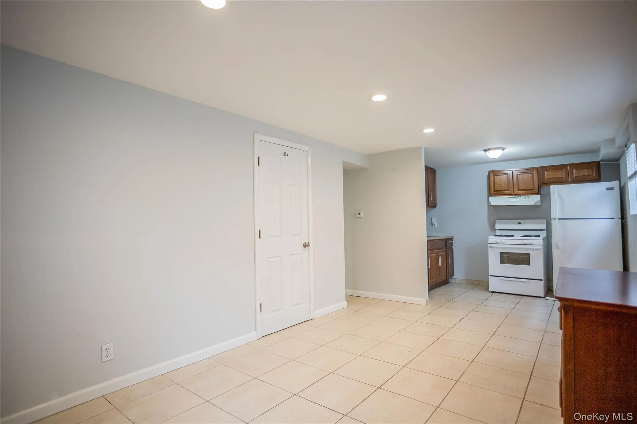 Kitchen featuring baseboards, white appliances, under cabinet range hood, recessed lighting, and light tile patterned flooring Kitchen featuring baseboards, white appliances, under cabinet range hood, recessed lighting, and light tile patterned flooring