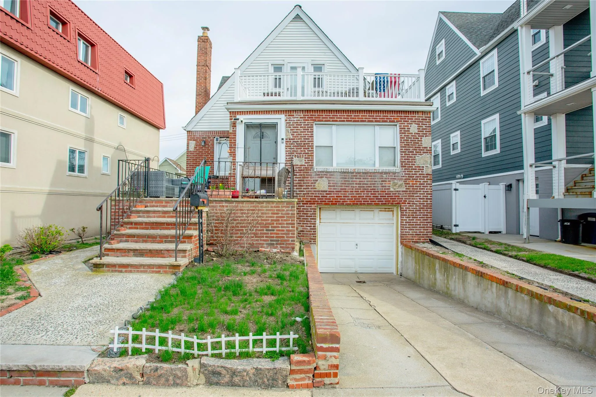 View of front facade with concrete driveway, a balcony, brick siding, a garage, and fence View of front facade with concrete driveway, a balcony, brick siding, a garage, and fence
