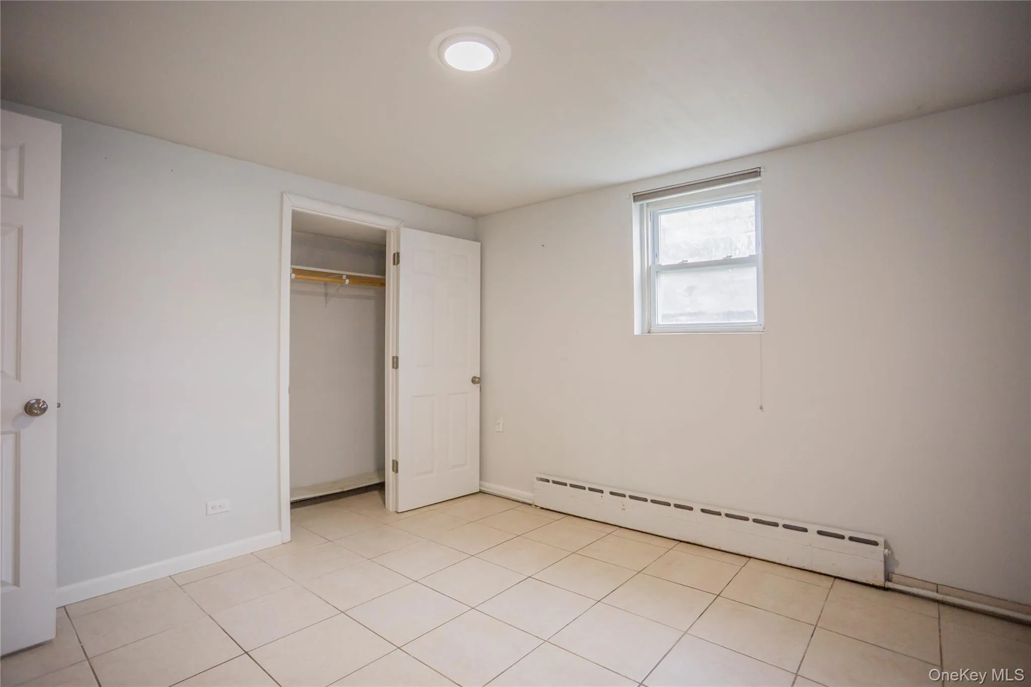 Unfurnished bedroom with a closet, a baseboard radiator, and baseboards Unfurnished bedroom with a closet, a baseboard radiator, and baseboards