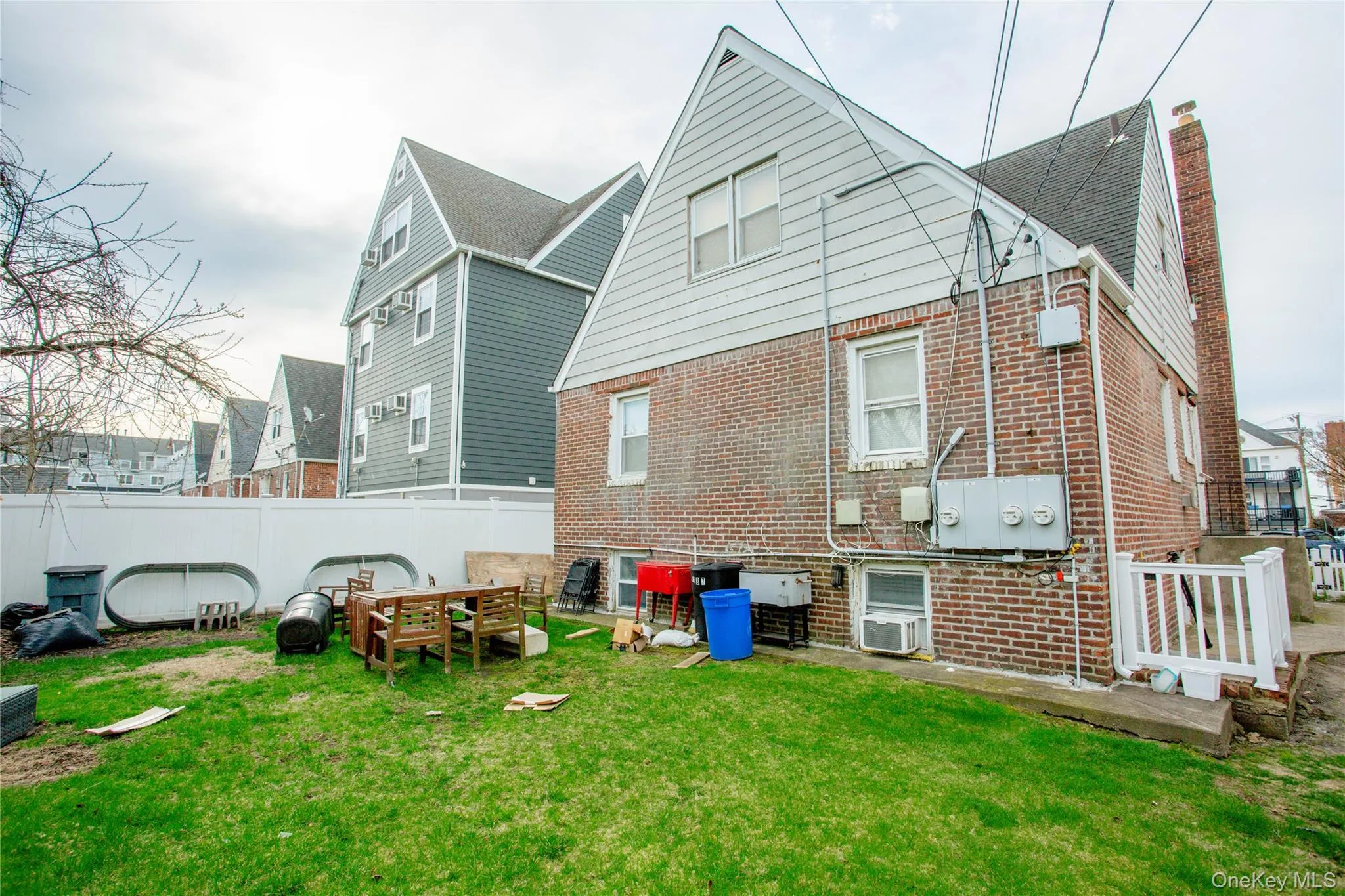 Rear view of property featuring a chimney, brick siding, fence, and a lawn Rear view of property featuring a chimney, brick siding, fence, and a lawn