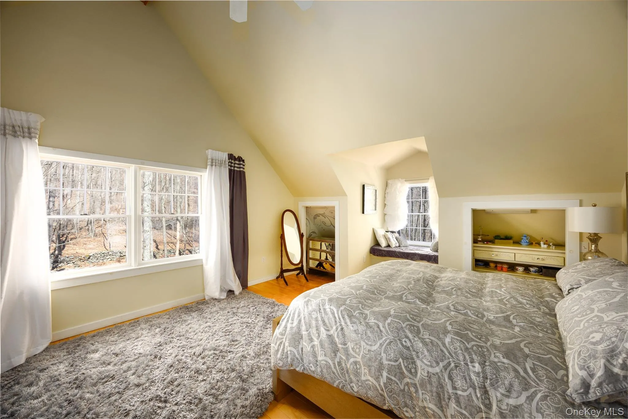 Bedroom featuring multiple windows, ceiling fan, lofted ceiling, and light wood-style floors Bedroom featuring multiple windows, ceiling fan, lofted ceiling, and light wood-style floors