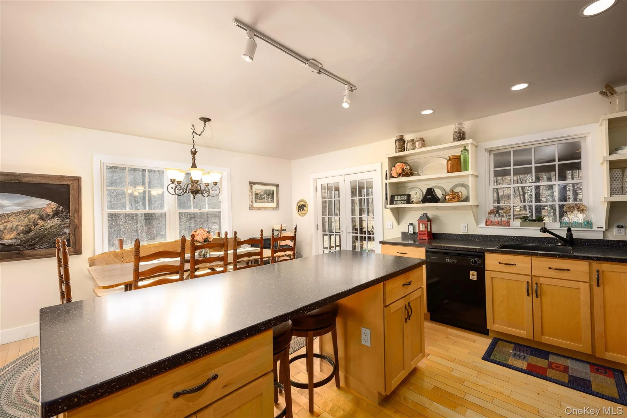 Kitchen with light wood-style floors, black dishwasher, rail lighting, a kitchen breakfast bar, and open shelves Kitchen with light wood-style floors, black dishwasher, rail lighting, a kitchen breakfast bar, and open shelves