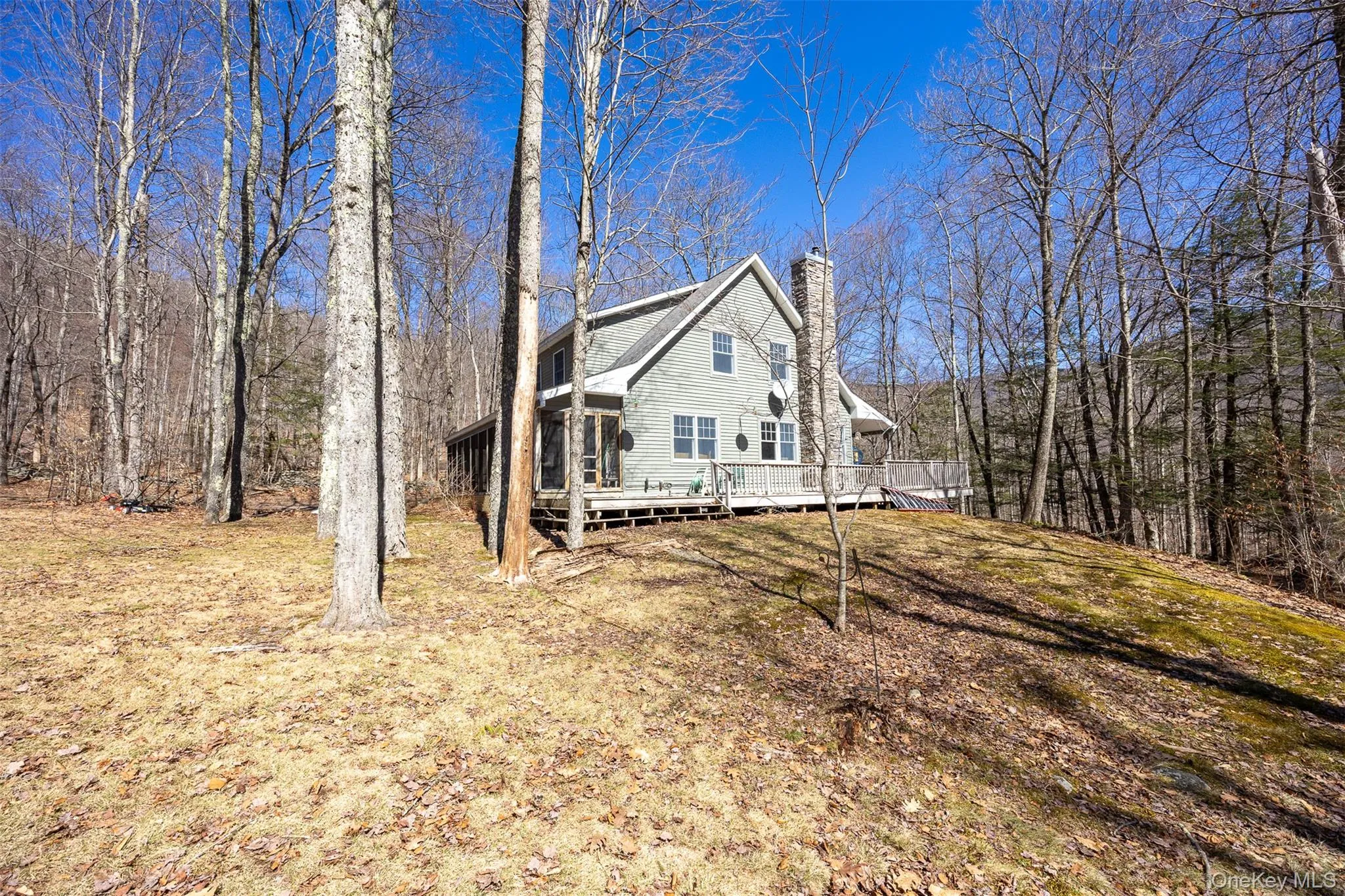 View of front of property with a chimney, a deck, and a front yard View of front of property with a chimney, a deck, and a front yard