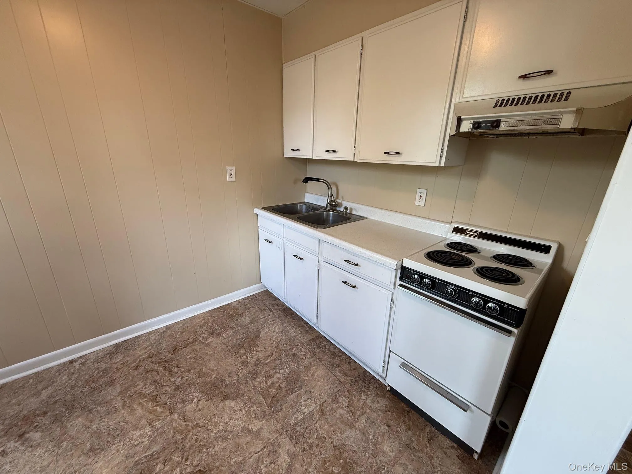Kitchen with white range with electric cooktop, exhaust hood, white cabinets, and light countertops Kitchen with white range with electric cooktop, exhaust hood, white cabinets, and light countertops