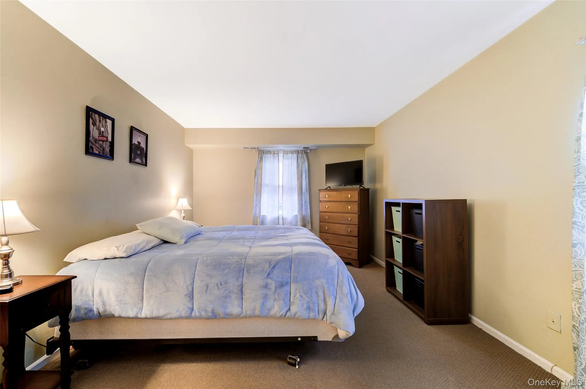Carpeted bedroom with neutral wall tones and a window with sheer curtains Carpeted bedroom with neutral wall tones and a window with sheer curtains