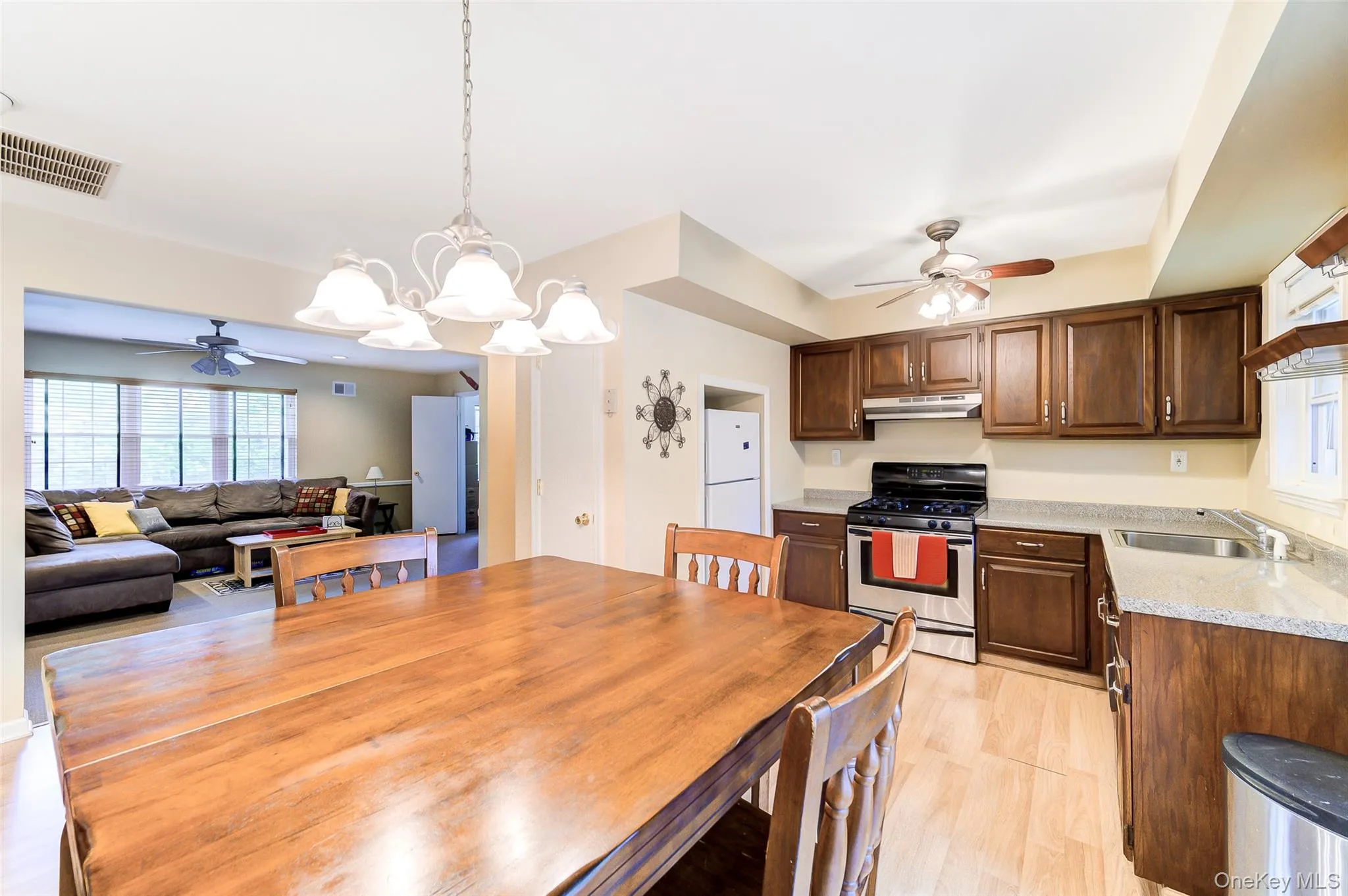 Kitchen and dining area featuring wood-finish flooring, dark wood cabinetry, light-toned countertops, and a stainless steel oven/range Kitchen and dining area featuring wood-finish flooring, dark wood cabinetry, light-toned countertops, and a stainless steel oven/range
