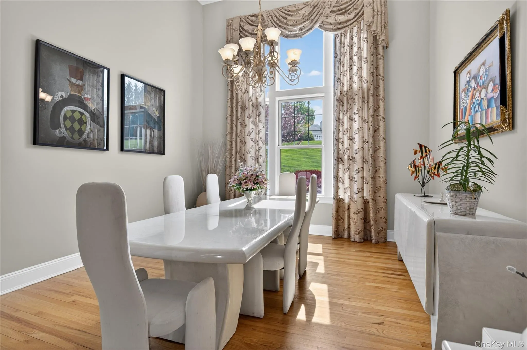 Formal dining room featuring hardwood flooring, oversized window with draped valance Formal dining room featuring hardwood flooring, oversized window with draped valance