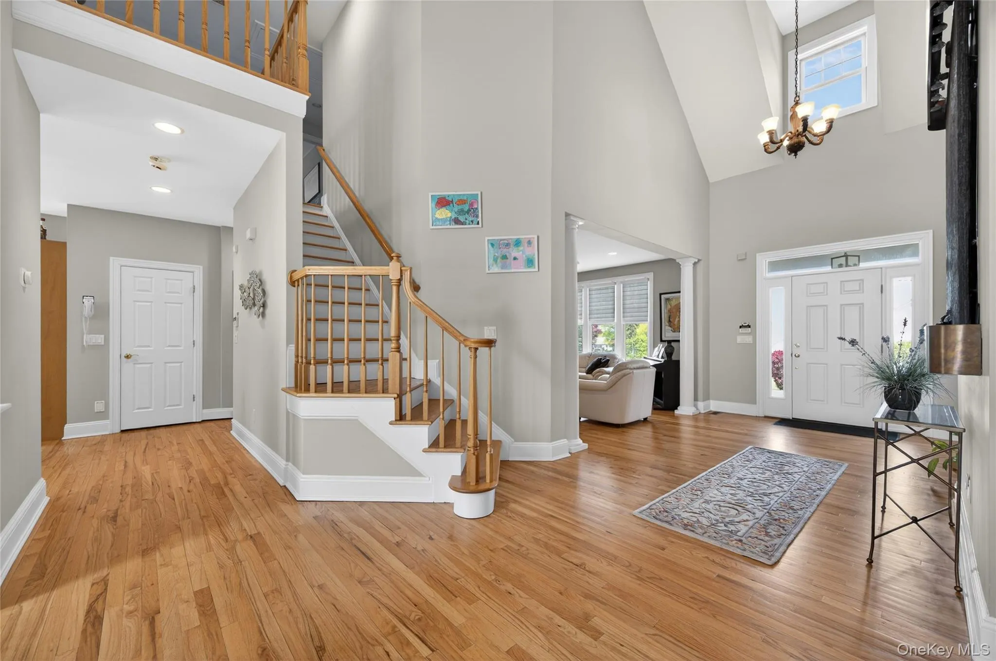 Foyer featuring wood-finish flooring and a grand staircase with wood banisters Foyer featuring wood-finish flooring and a grand staircase with wood banisters