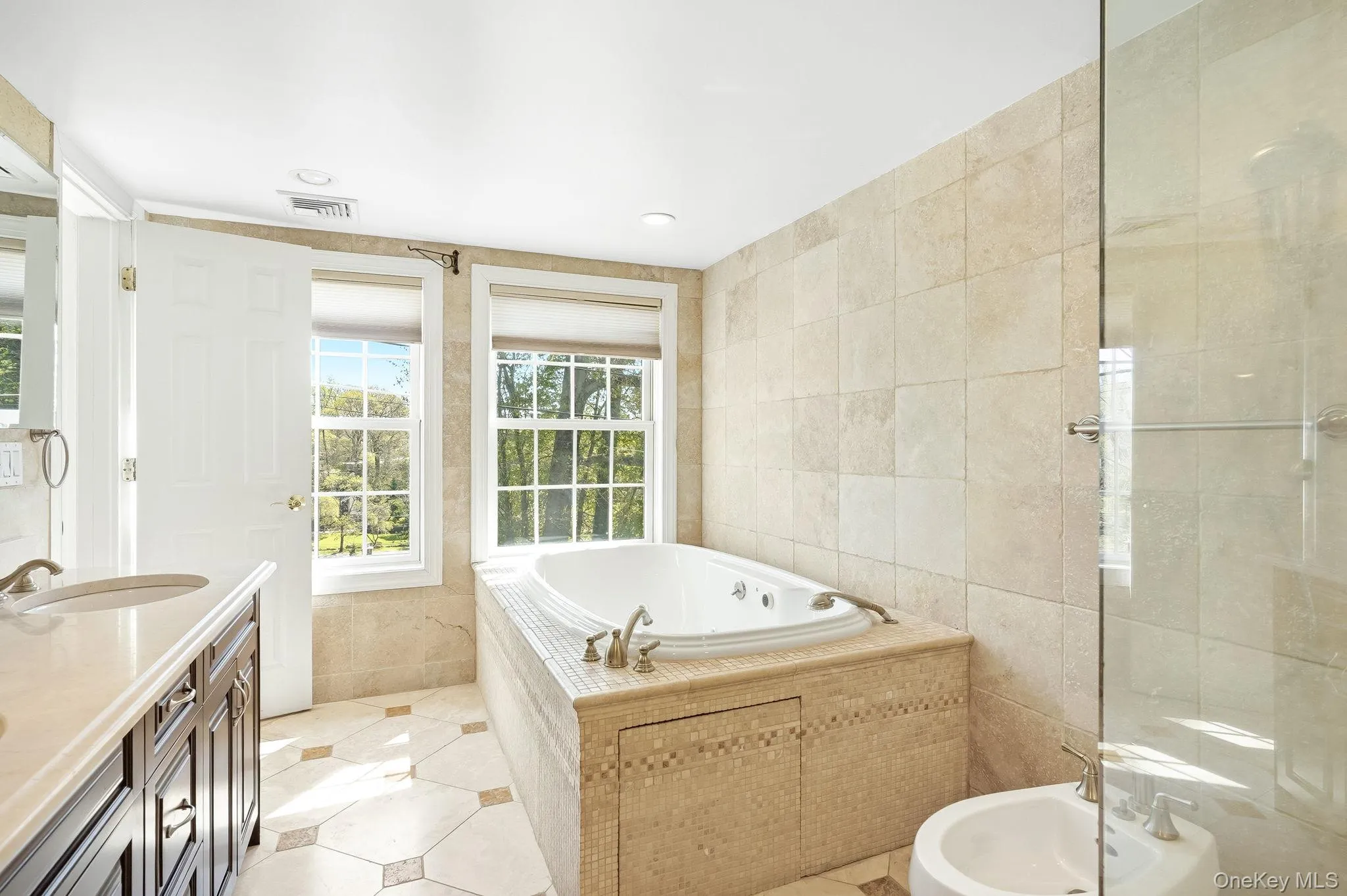 The primary spa like bathroom offers a jetted tub, beautiful tile surround, dual windows, and an enclosed glass shower The primary spa like bathroom offers a jetted tub, beautiful tile surround, dual windows, and an enclosed glass shower