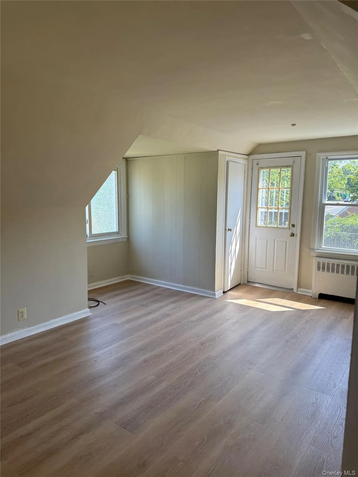 Additional living space with vaulted ceiling, wood finished floors, and radiator heating unit Additional living space with vaulted ceiling, wood finished floors, and radiator heating unit